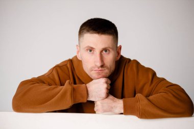 Thoughtful portrait and intelligent look of a 30-year-old guy who is married. Brown sweatshirt on a white background