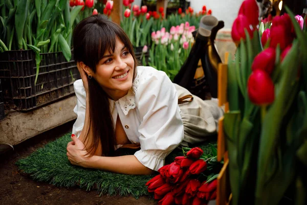 A girl has an antique camera. Greenhouse with tulips. Bright smile