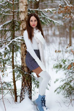 Genç bir kadın kar atıyor. Güneşli bir kış gününde karla oynayan mutlu bir kadının portresi. Kış ormanında bir yürüyüş. Eğlence kavramı, rahatlama..