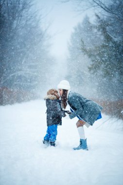 Anne ve oğlu kışın ormanda yürüyorlar. Şiddetli kar yağıyor. Çocukların mutluluğu. Ocak 'ta kalın giysiler