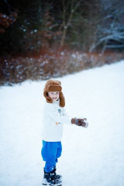 Güzel kış parkında diliyle kar taneleri yakalayan sevimli küçük çocuk.