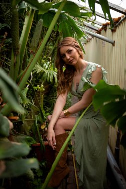 A beautiful young woman is holding a large green leaf. Hot sunny day. Rest on a tropical island. Summer travel girl, active lifestyle.