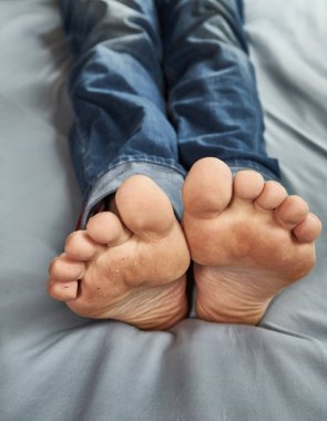 Erkekler yatakta yalınayak yatıyor.