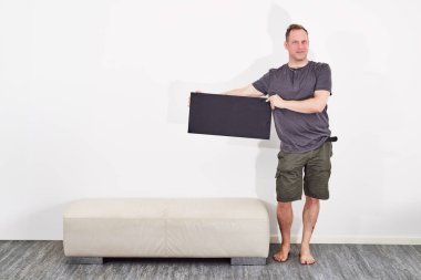 Siyah tabela tutan şortlu adam çıplak ayaklı.