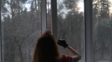 Kırmızı kareli elbiseli ve kırmızı kurdeleli bir kız evi temizliyor. Orman manzaralı bir pencere açar, penceredeki kiri sabunlu bez, sabunlu solüsyon ve sprey silahla temizler..