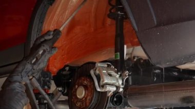 Araba servisi, bir işçi korozyon önleyici sürmeden önce arka kemerleri çamurdan yıkar. Yüksek kalite 4k görüntü