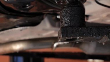 Bir araba servisinde asansörde tamir edilen arabanın altından su akar. Kameranın kablosu asansörün ayağının altından makinenin tabanına kadar uzanıyor. Yüksek kalite 4k görüntü