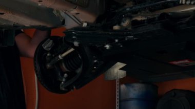 Tamirci araba servisinde çalışıyor. Aile işi konsepti. Bir araba atölyesinde çalışma. Araba tamirhanesinde araba tamirciliği yapan profesyonel bir tamirci. Bir araba atölyesinde çalışma yüksek kaliteli 4K görüntü