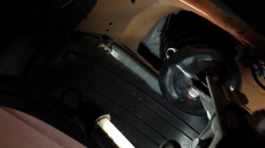 Araç motorunun arka planına karşı, benzin istasyonu çalışanı tekerlek kemerinin plastik koruyucusunu almaya ve çıkarmaya çalışır. Yüksek kalite 4k görüntü