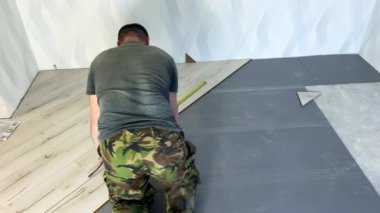 Kiralık bir işçi, tabakanın altına döşemek için zemini işaretliyor. Bir adam yeni bir evin zeminine ahşap kaplama döşemiş. Yüksek kalite 4k görüntü