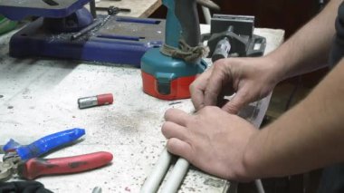 Atölyedeki bir masada adamın biri plastik bir uzatma kablosu hazırlıyor. Başlıklı adaptörü çubuğa kadar sürüklemek için bir delik açıyor. Yüksek kalite 4k görüntü