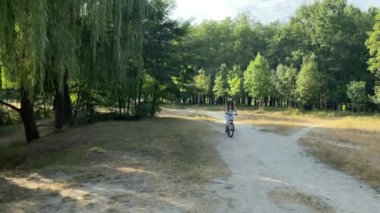Genç bir kadın hafta sonu parkta bisiklet sürmekten hoşlanır. Göl kenarında tatilde olan çekici bisikletçi kız, aktif bir hayat sürüyor, parkta yürüyüş yapıyor ve tatilde boş vakit geçiriyor.