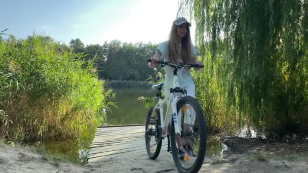 Uma Menina Com Uma Bicicleta Uma Ponte Madeira Perto Lago — Vídeo de Stock