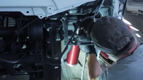 一名戴着棒球帽和呼吸器的工人在卡车驾驶室的车轮拱和其他金属部件表面喷涂防腐蚀黑蜡 防锈筒4K镜头 — 图库视频影像