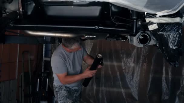 在悬挂在电梯上的汽车下 车体维修主把所有不需要用防腐蚀液体处理的部件包扎起来 修车高质量的4K镜头 — 图库视频影像