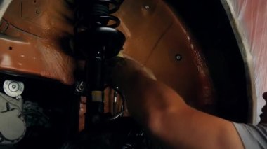 Tekerlek kemerinin korozyon önleyici tedaviye hazırlanması. Servis merkezinin çalışanı asansörde asılı duran arabaya bakıyor. Vücudunda esnemeyle maskelenmiş yerler arıyor.