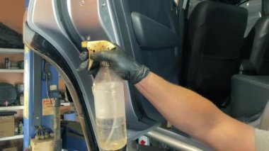 Pası silmek için araba kapılarına beyaz ruh sıkmak. Usta, kapı ve kapı kartındaki tüm pasları kimyasal bir sıvıyla kaldırıyor. Aseton. Arabanın metal yüzeyindeki pasın çıkarılması..