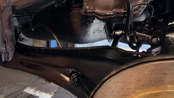 クルマ スプリング 排気パイプのリアアクスルは 黒ワックスで治療した後 クルマの底部に反腐食処理が施された結果です 車の金属ベースに適用されるワックスの黒い痕跡 — ストック動画