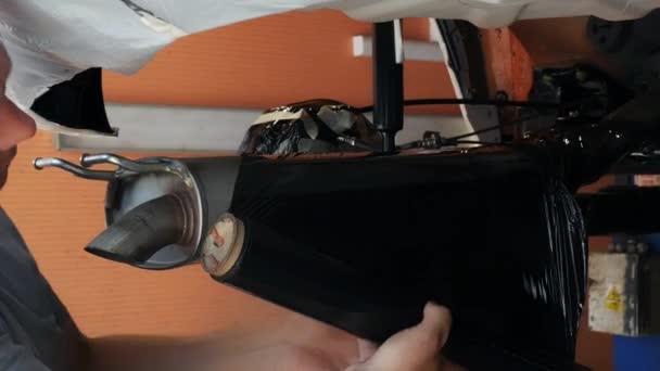 Homem Envolve Tubo Escape Carro Com Filme Stretch Garagem Mestre — Vídeo de Stock