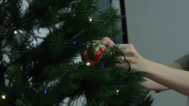 Güzel genç bir kadın evdeki Noel ağacına Noel süsleri asıyor ve gülümsüyor, çok mutlu. Yüksek kalite 4k görüntü