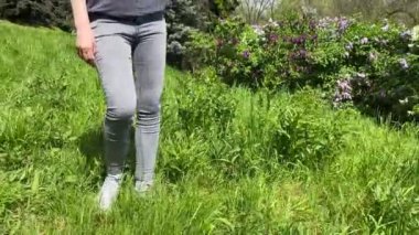 Kız poz veriyor ve çiçekli bitkilerin arka planında uzun saçlarını sallıyor. Genç bir kızın uzun kızıl saçları. Bir kadın botanik bahçesinde saçını savururken dönüyor. Bahar günü. Çiçek açan bitkiler. 