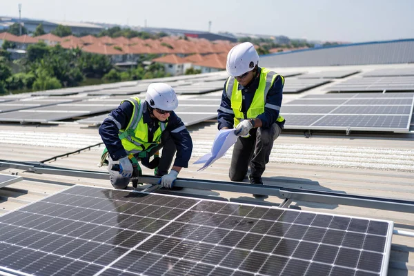 屋顶工程师跪在太阳能电池板旁边进行光电检查 以确保安装良好 — 图库照片