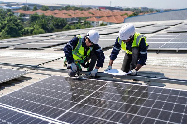 屋顶工程师跪在太阳能电池板旁边进行光电检查 以确保安装良好 — 图库照片