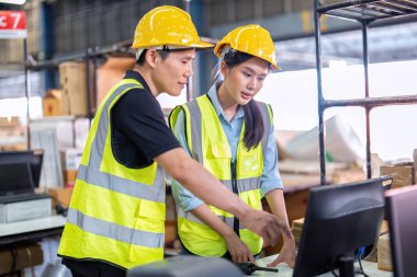 Geniş depo deposunda çalışan personel stajyer öğrenci kutusunu kontrol ediyor ve kasiyeri tarıyor.
