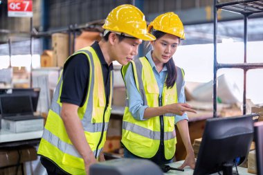 Geniş depo deposunda çalışan personel stajyer öğrenci kutusunu kontrol ediyor ve kasiyeri tarıyor.