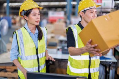 Geniş depo deposunda çalışan personel stajyer öğrenci kutusunu kontrol ediyor ve kasiyeri tarıyor.