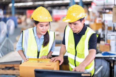 Geniş depo deposunda çalışan personel stajyer öğrenci kutusunu kontrol ediyor ve kasiyeri tarıyor.