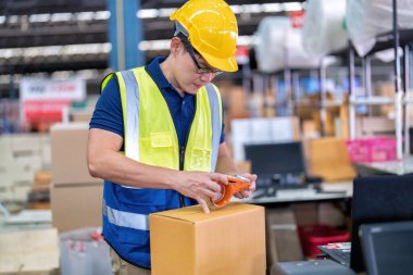 Büyük depo deposunda çalışan işçiler yapışkan bant kullanırlar. Kasiyerde paket kutusu hazırlarlar.