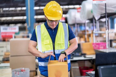Büyük depo deposunda çalışan işçiler yapışkan bant kullanırlar. Kasiyerde paket kutusu hazırlarlar.