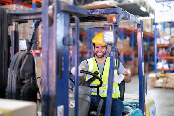 Forklift Truck Operator Lifts Pallet Cardboard Boxes On a Shelf by Trucks smiling portrait
