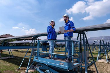 Güneş çiftliğindeki bakım mühendisleri makas kaldırma, güneş panellerini teftiş ve radyo raporları üzerinde duruyorlar. 