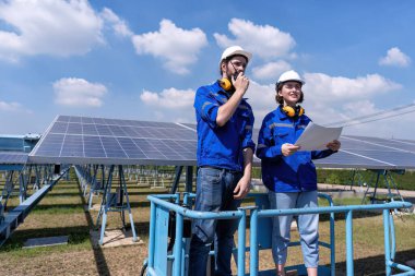 Güneş çiftliğindeki bakım mühendisleri makas kaldırma, güneş panellerini teftiş ve radyo raporları üzerinde duruyorlar. 