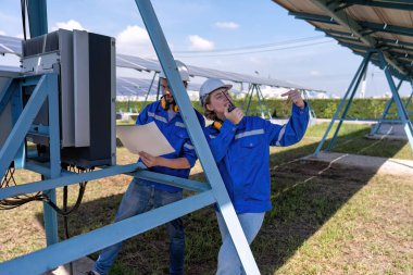 Güneş çiftliğindeki bakım mühendisleri ters çevirme kontrol paneline bakarak çekim yaparken sorun yaşıyorlar.