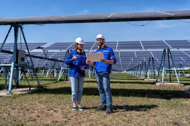 Güneş çiftliğindeki bakım mühendisleri elektrik santralinin genişletilmesi konusunu tartıştılar.