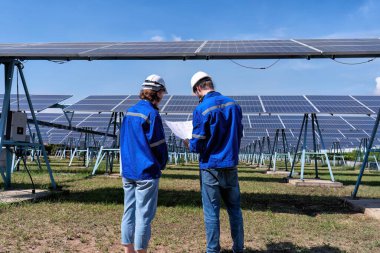 Güneş çiftliğindeki bakım mühendisleri elektrik santralinin genişletilmesi konusunu tartıştılar.