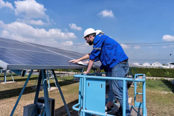 太陽光発電所のメンテナンスエンジニアは ディスクリフトの上に立つ 太陽電池パネルの状態の定期的な検査 — ストック写真