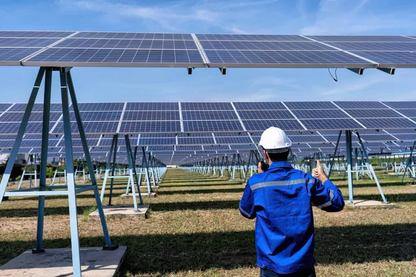 Maintenance engineer at solar farm produce clean electricity walking under solar panel radio to team