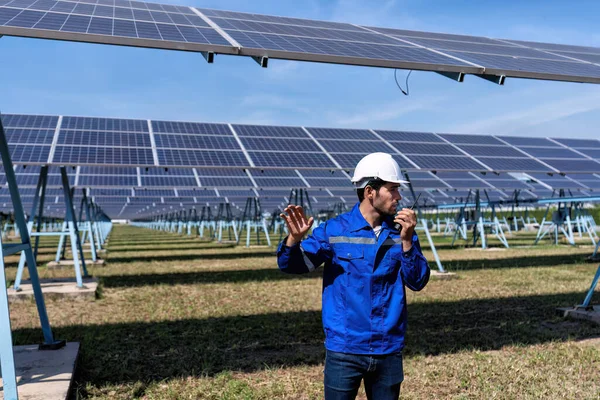 Maintenance engineer at solar farm produce clean electricity walking under solar panel radio to team