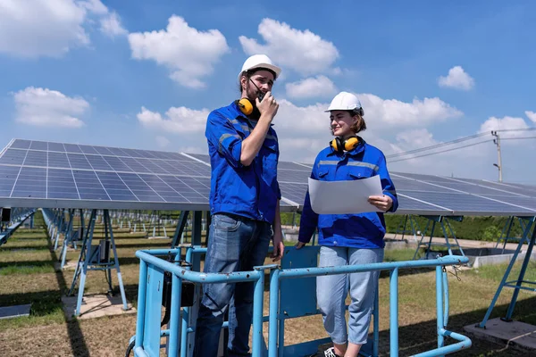 太阳能站的维修工程师在剪切机升降机上 检查太阳能电池板和进行无线电报道 免版税图库图片