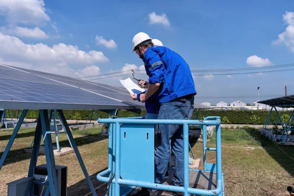 太阳能发电场站维修工程师在剪切机升降机上 定期检查太阳能电池板状况 免版税图库照片