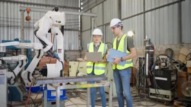 Robot eğitim eğitmeninde kız mühendise dizüstü bilgisayardan robot kolu görünüş kılavuzunu programlamayı öğret