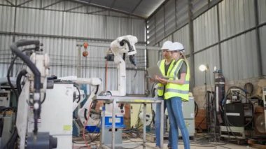 Robot eğitim eğitmeninde kız mühendise dizüstü bilgisayardan robot kolu görünüş kılavuzunu programlamayı öğret