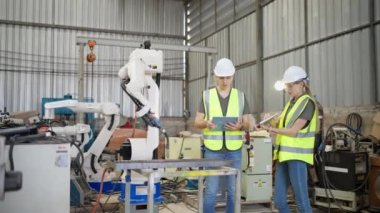 Robot eğitim eğitmeninde kız mühendise dizüstü bilgisayardan robot kolu görünüş kılavuzunu programlamayı öğret