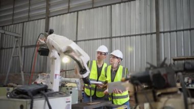 Robot eğitim eğitmeninde kız mühendise dizüstü bilgisayardan robot kolu görünüş kılavuzunu programlamayı öğret