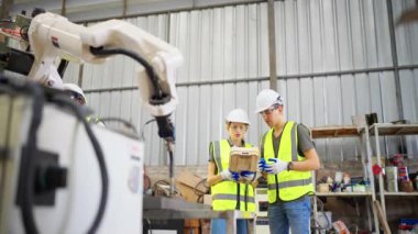 Robot eğitim merkezinde kız mühendise robot kolu nasıl çalıştırıp programlayacağını öğretiyor.