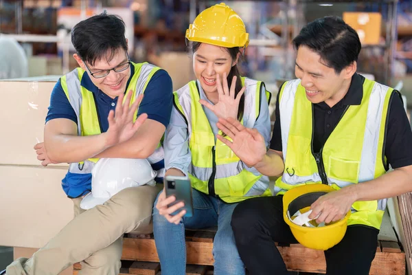 Staff in large storage warehouse together sit back relax funny laughing check mobile phone